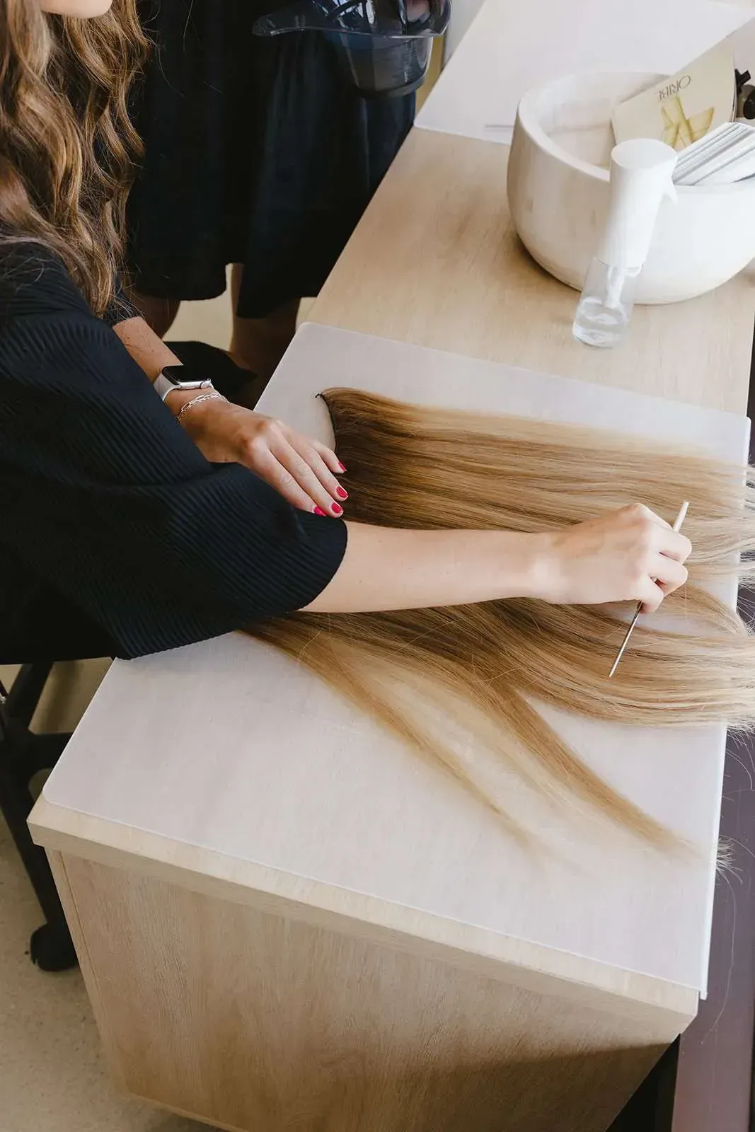 A woman is sitting at a table with a bunch of hair on it.