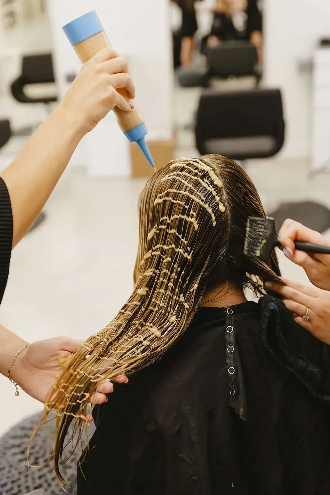 A woman is getting her hair dyed in a salon.