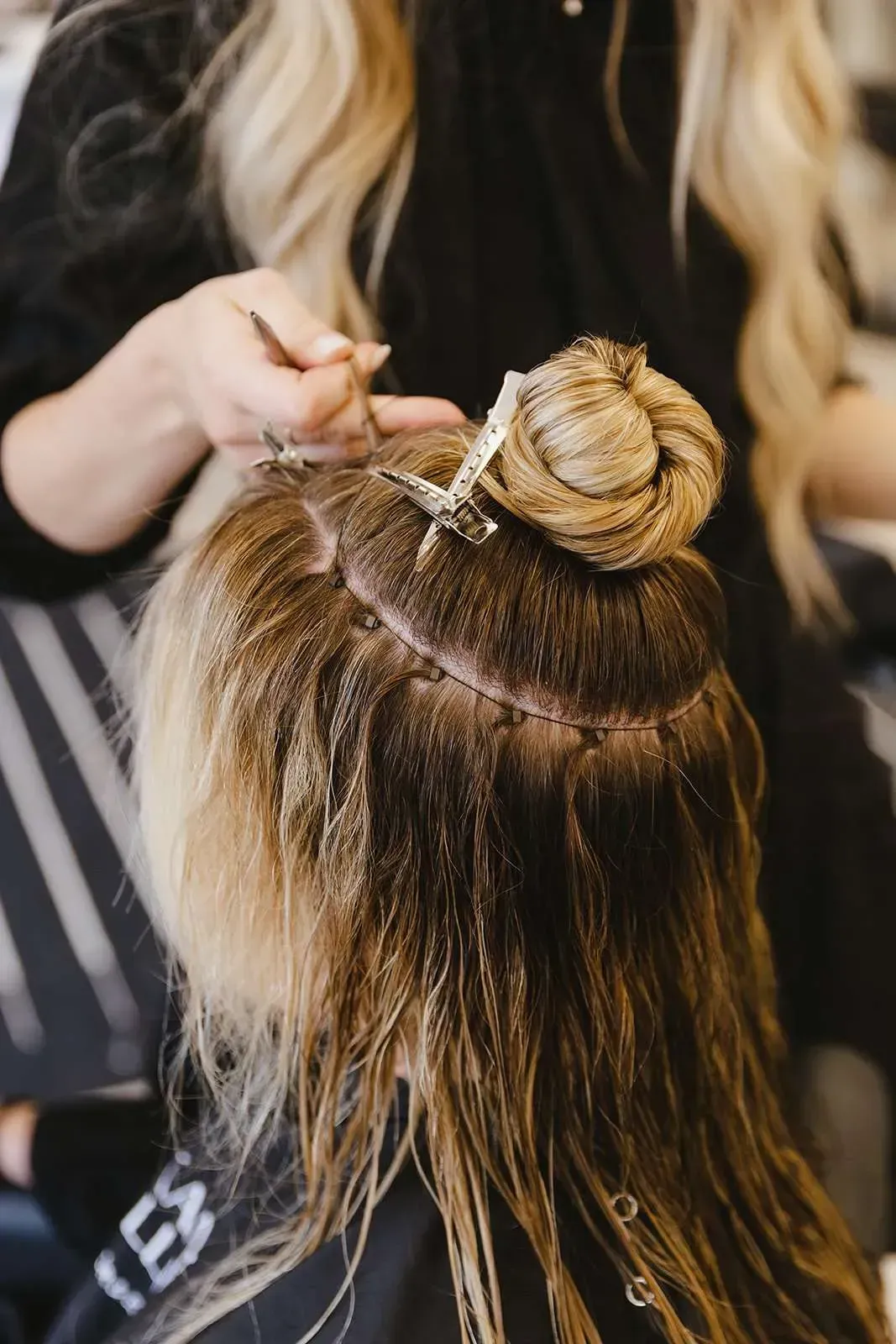 A woman is getting her hair done by a hairdresser in a salon.