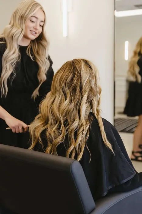 A woman is getting her hair done by a hairdresser in a salon.