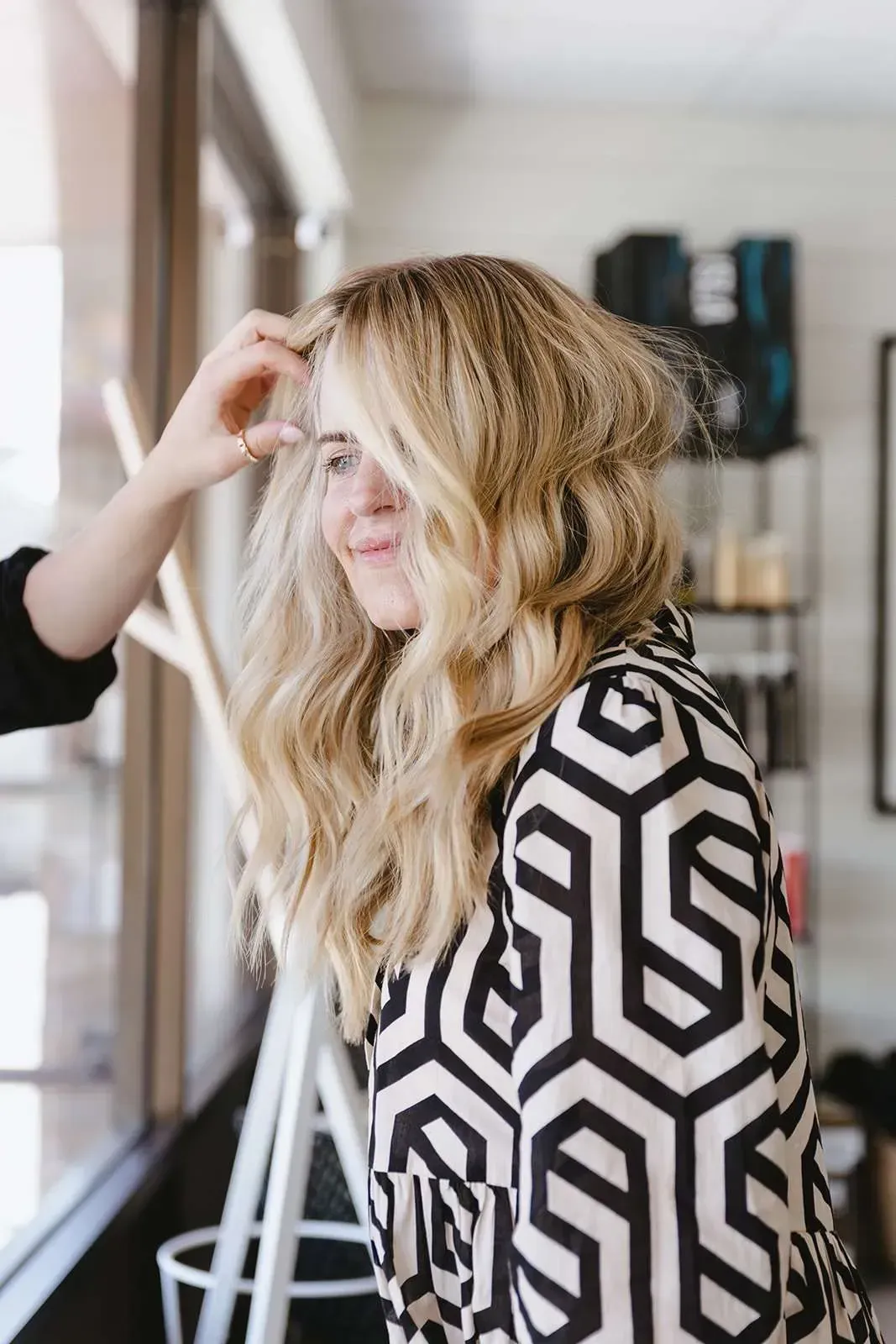 A woman is getting her hair done by a hairdresser in a salon.