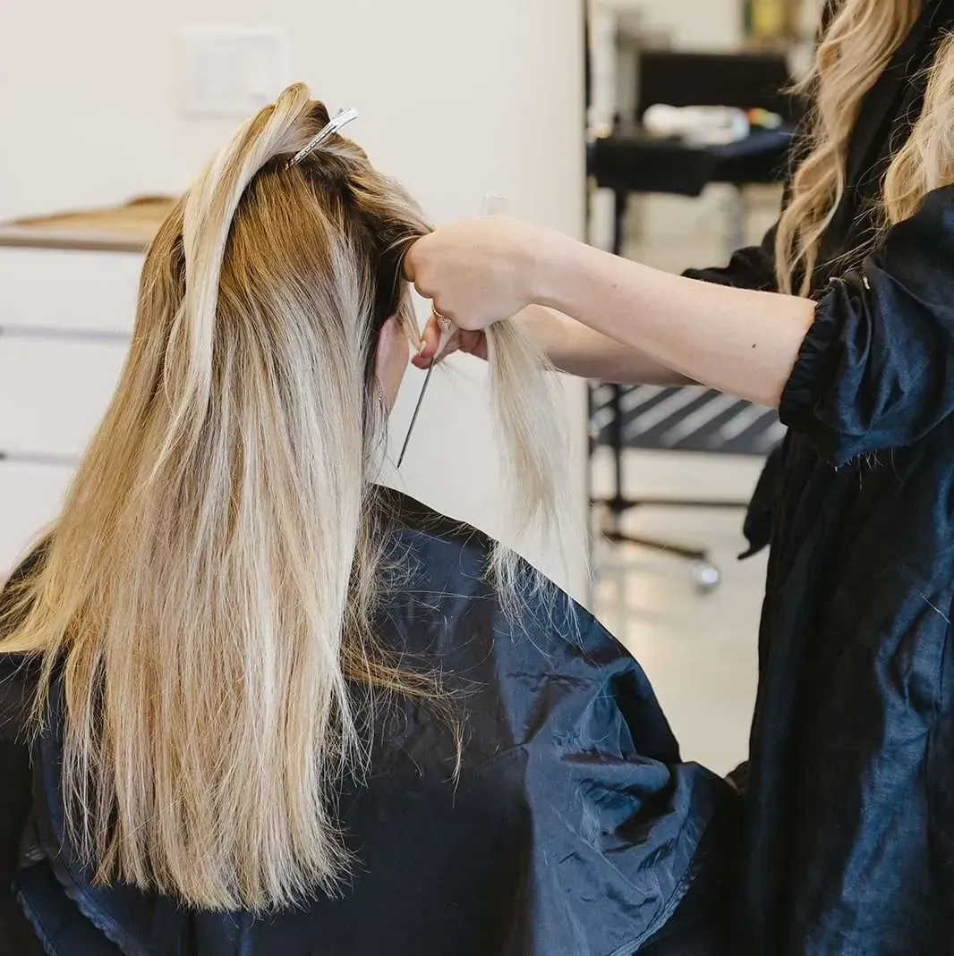 A woman is getting her hair cut by a hairdresser in a salon.