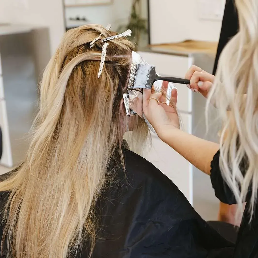 A woman is getting her hair dyed by a hairdresser in a salon.