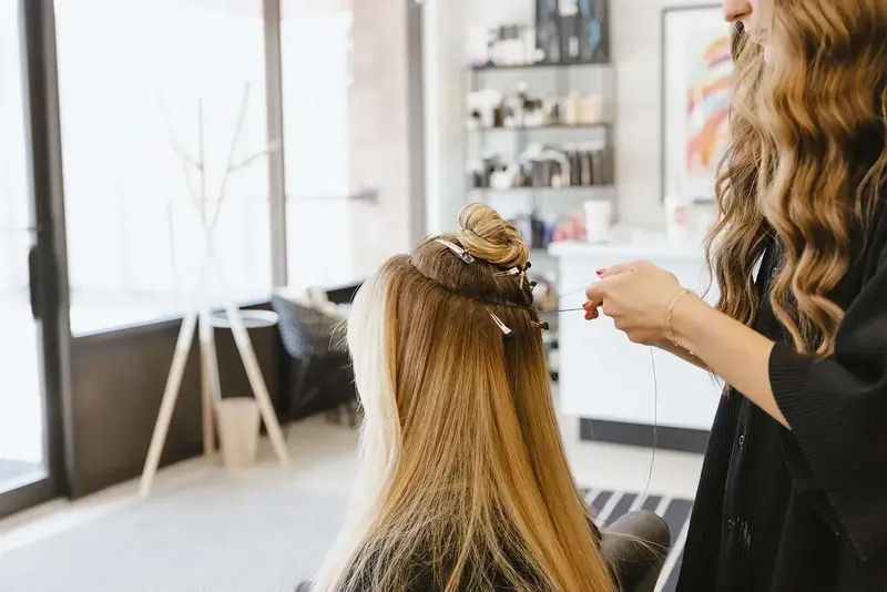 A stylist talks with a guest about her extension goals in the salon chair