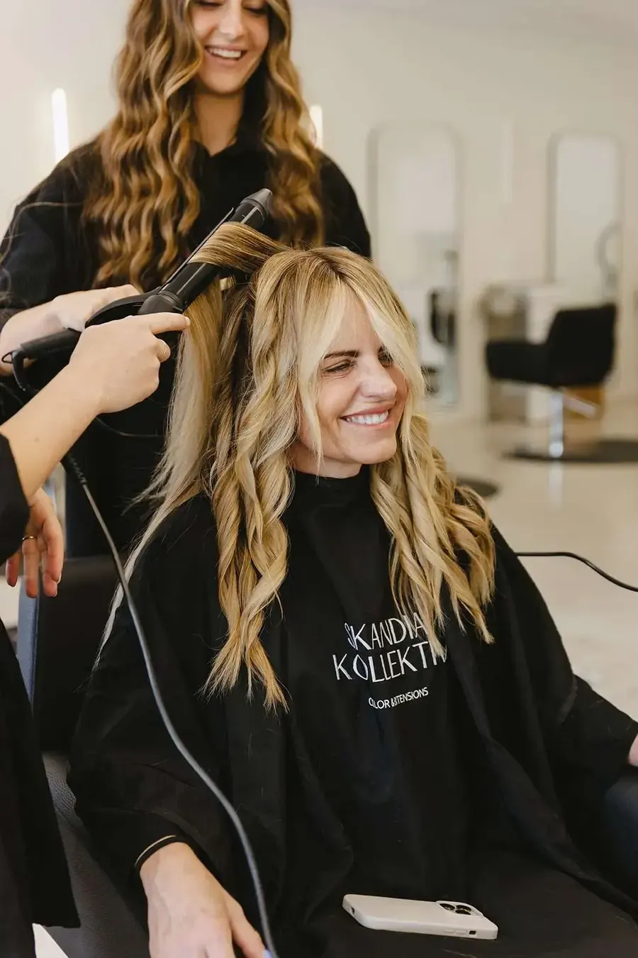 A smiling guest with long, styled blonde hair extensions at Skandia Kollektiv